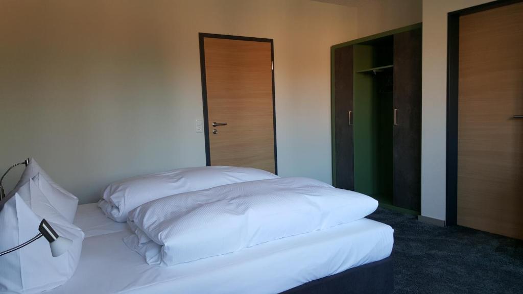 Cama blanca en habitación con 2 puertas en Hotel Landhaus Feyen en Großefehn 