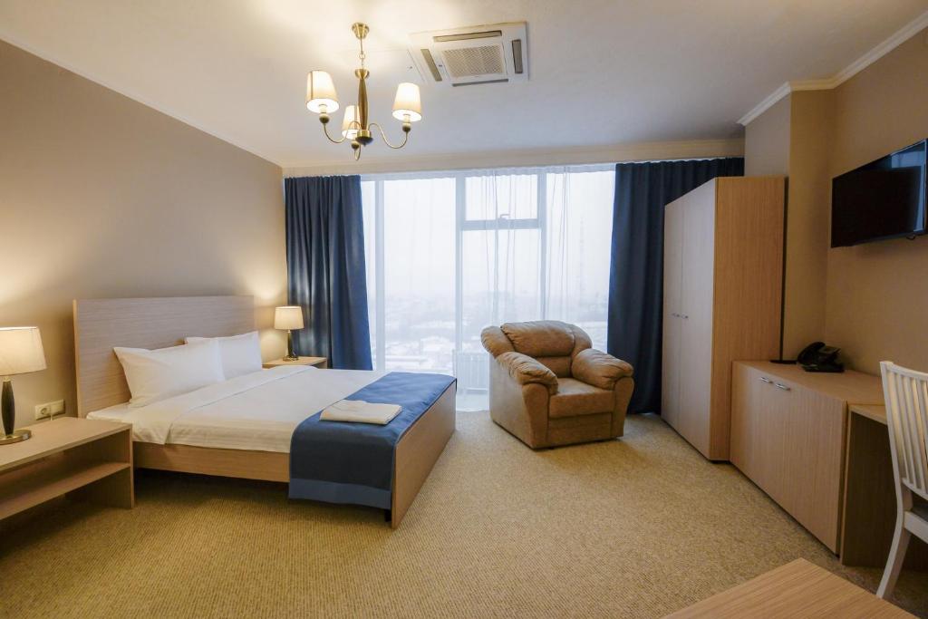 ヴォロネジにあるZastava Hotelのベッド1台、椅子、窓が備わる客室です。