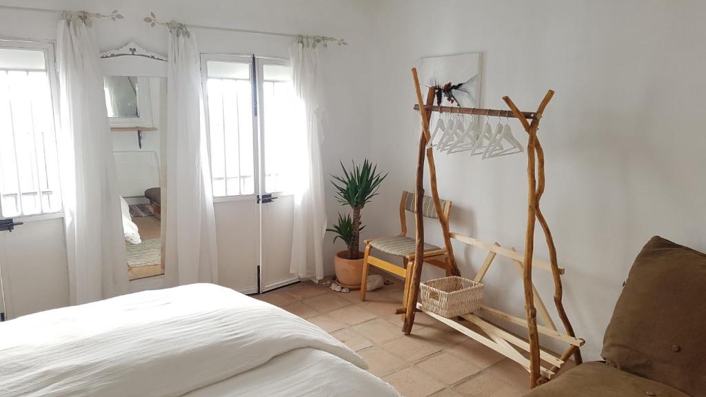 1 dormitorio con cama, silla y espejo en Cortes de la Frontera Townhouse, en Cortes de la Frontera