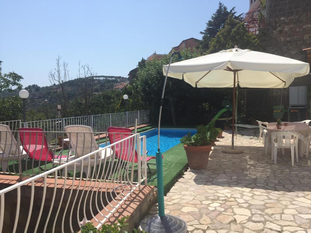una piscina con sedie e ombrellone accanto a una piscina di Villa Asia a SantʼAgata sui Due Golfi