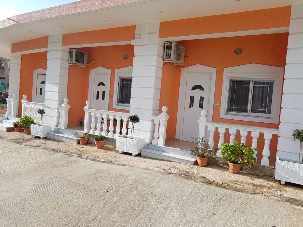 ein orangefarbenes Gebäude mit Topfpflanzen davor in der Unterkunft Villa Nicolaos Ksamil in Ksamil
