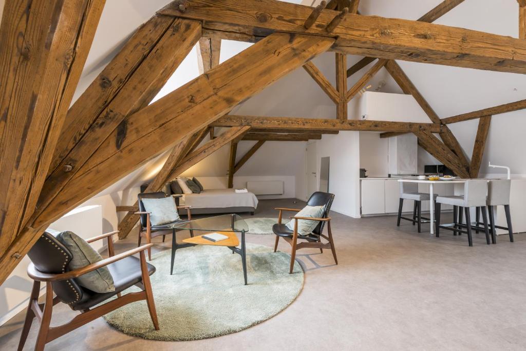 a loft with wooden beams and chairs and a table at Obelisque in Bruges