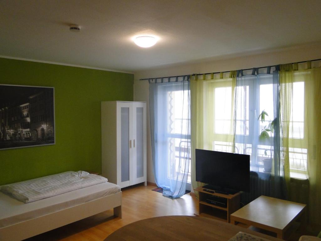 un soggiorno con pareti verdi, un letto e una TV di Cityappartment am Stadttheater a Friburgo in Brisgovia