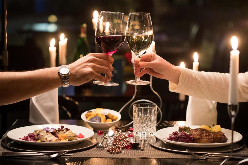 two people holding glasses of wine at a table with food at Wyndham Stuttgart Airport Messe in Stuttgart