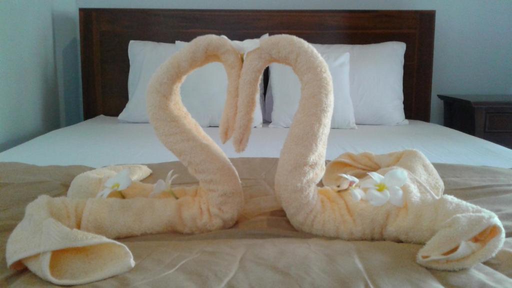 two towelsrendered to look like swans on a bed at Kuwera Homestay in Nusa Penida