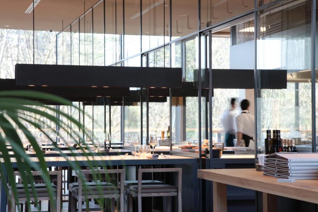 a restaurant with a bar with green chairs and windows at Hotel Arima & Spa - Small Luxury Hotels in Donostia-San Sebastián