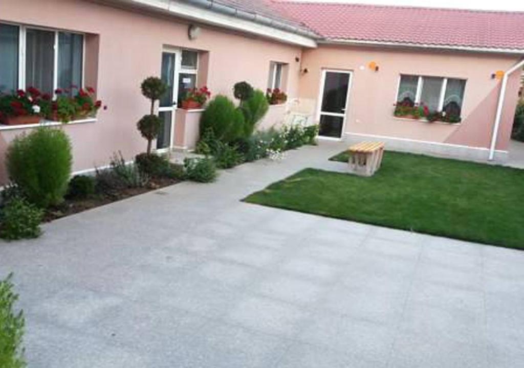 a courtyard of a house with a lawn and a bench at Pensiunea Gheorghita in Haţeg