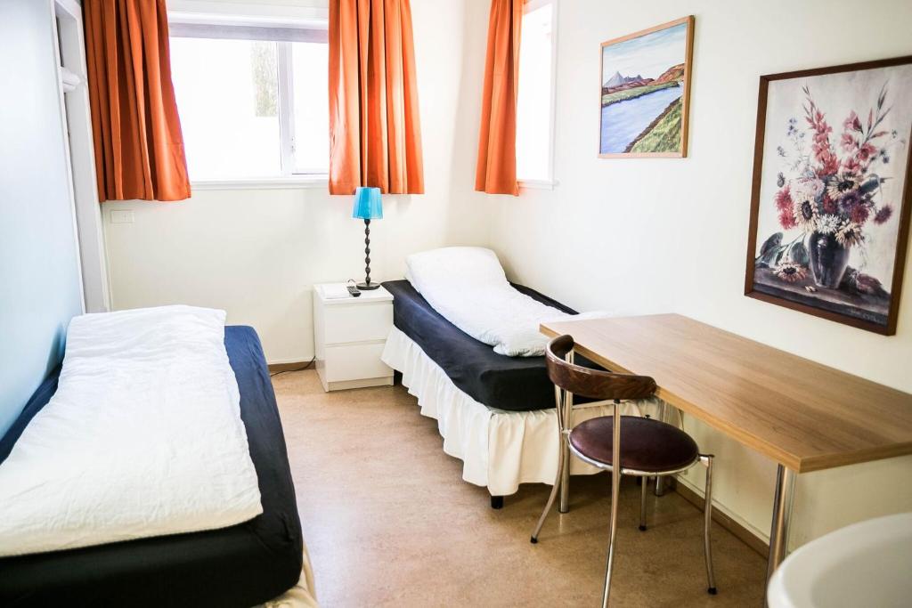 a room with two beds and a desk and a table at Igdlo Guesthouse in Reykjavík