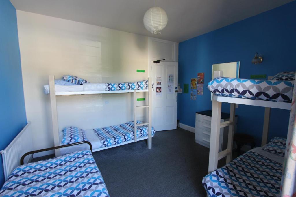 a room with three bunk beds with blue walls at Pitlochry Backpackers in Pitlochry