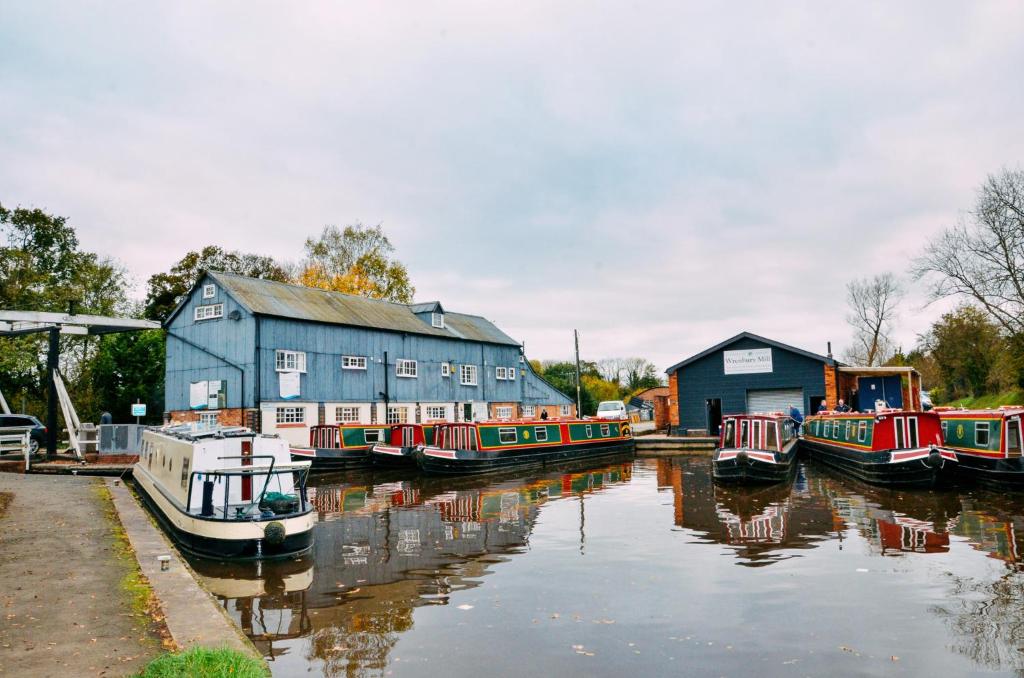 un gruppo di barche è ormeggiato accanto a un edificio di Wrenbury Mill Apartment a Wrenbury