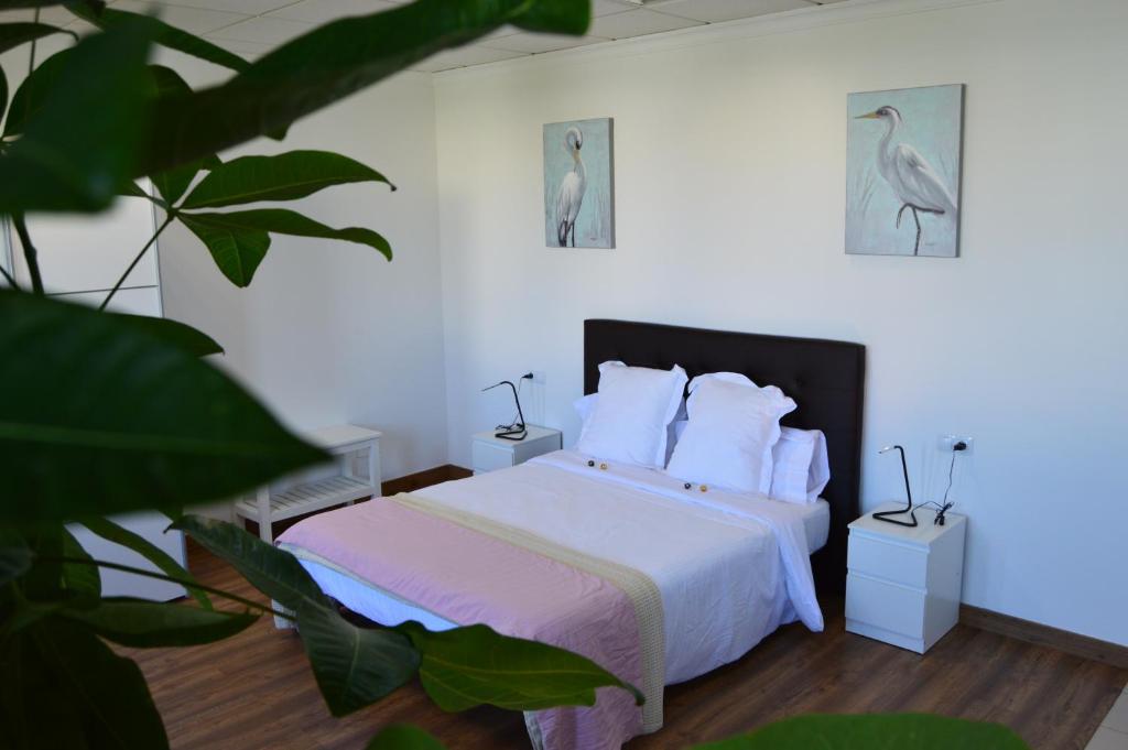 um quarto com uma cama com lençóis brancos e uma imagem de pássaro em Moai Loft em Arrecife