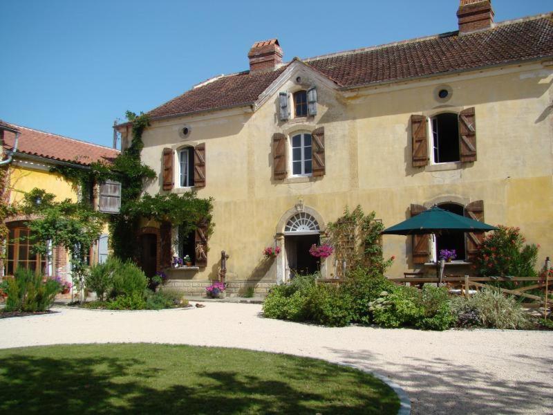 una casa grande con una sombrilla delante de ella en Au Balenti, en Lascazères
