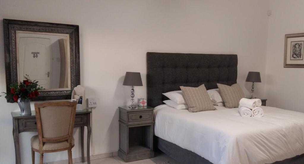um quarto com uma cama, um espelho e uma cadeira em Aspasia Agency CC em Mariental