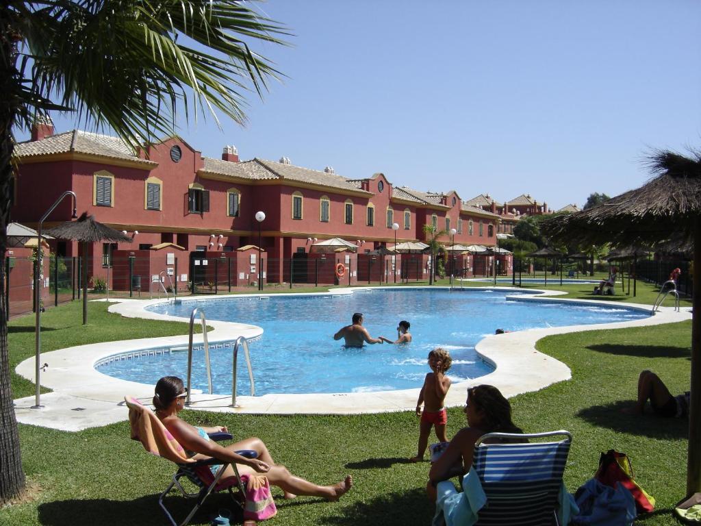 un grupo de personas sentadas alrededor de una piscina en Bonito adosado playas Islantilla, en Islantilla