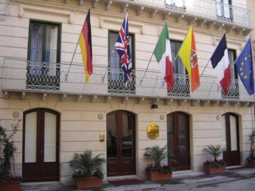un edificio con banderas a un lado. en Hotel Residence Le Chiavi Di San Francesco, en Trapani