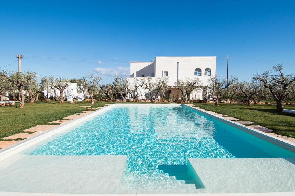 a swimming pool in front of a white house at Masseria Spesseto in Montalbano