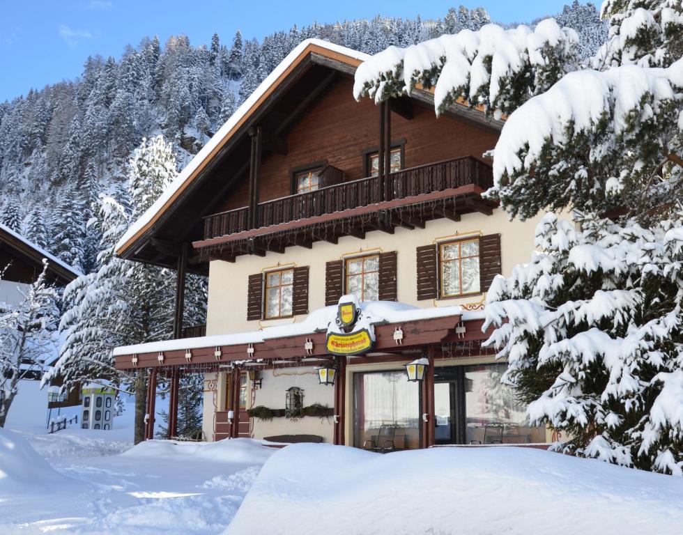 uma cabana de madeira na neve com árvores cobertas de neve em Gästehaus Christophorus em Innerkrems