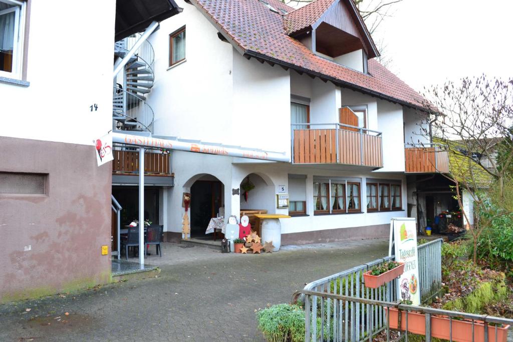 ein großes weißes Haus mit einem Balkon und einem Tor in der Unterkunft Gästehaus Tagescafe Eckenfels in Ohlsbach