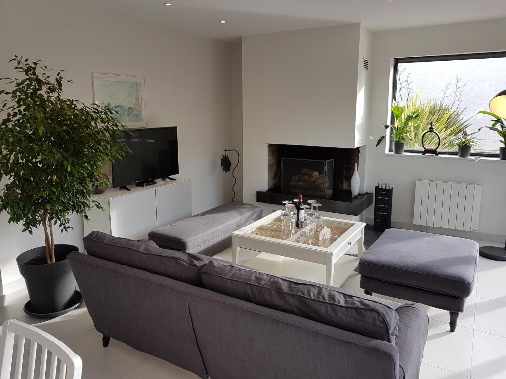 Una sala de estar con un sofá y un televisor. en Le lodge, en Vaux-sur-Mer