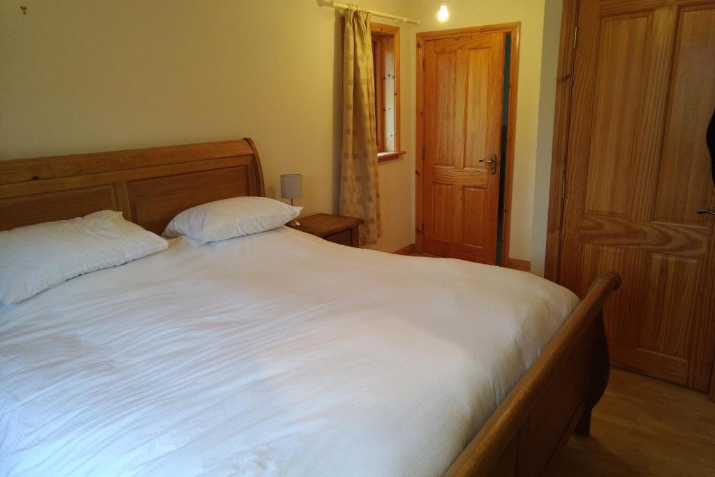 um quarto com uma grande cama branca e 2 almofadas em 14 Drumcoura Lake Resort em Ballinamore