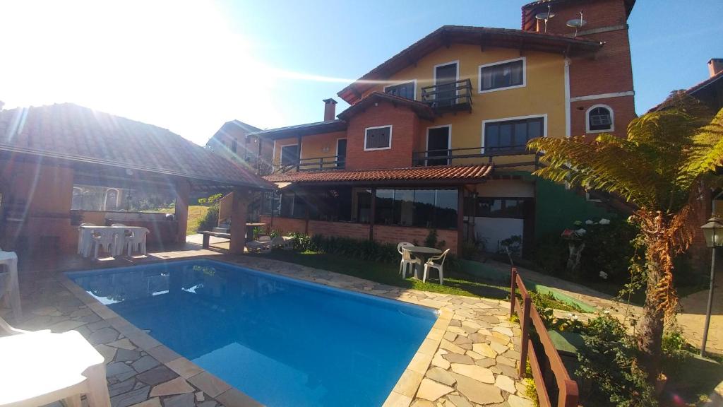 una casa con piscina delante de una casa en Pousada Palma Chalés, en Monte Verde