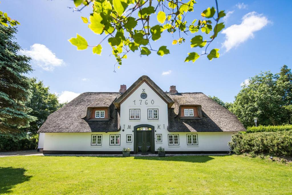 ein großes weißes Haus mit schwarzem Dach in der Unterkunft Landhaus Treskersand in Tinnum