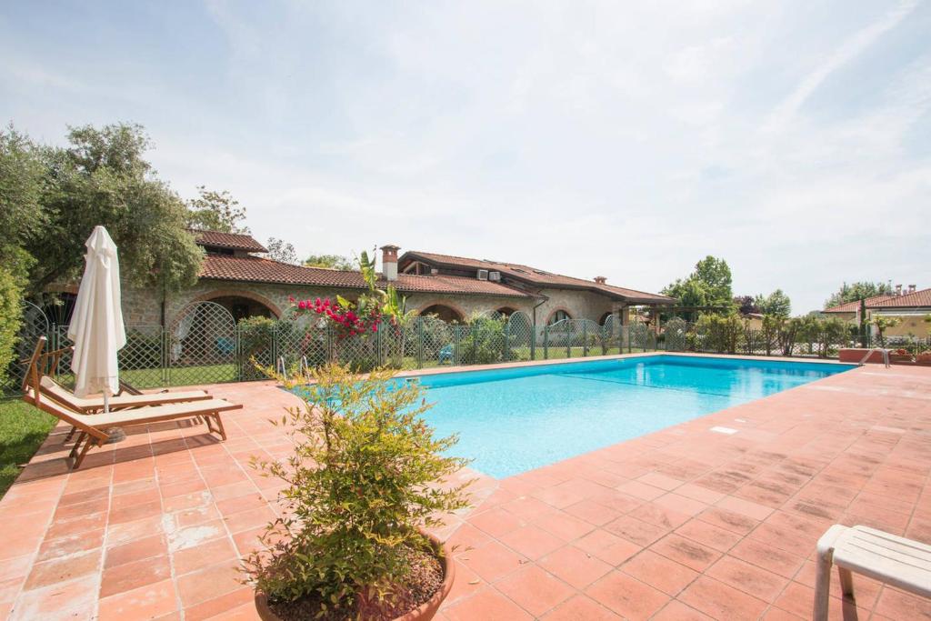 a swimming pool with a chair and a umbrella at Luxury Tuscan House in Pietrasanta