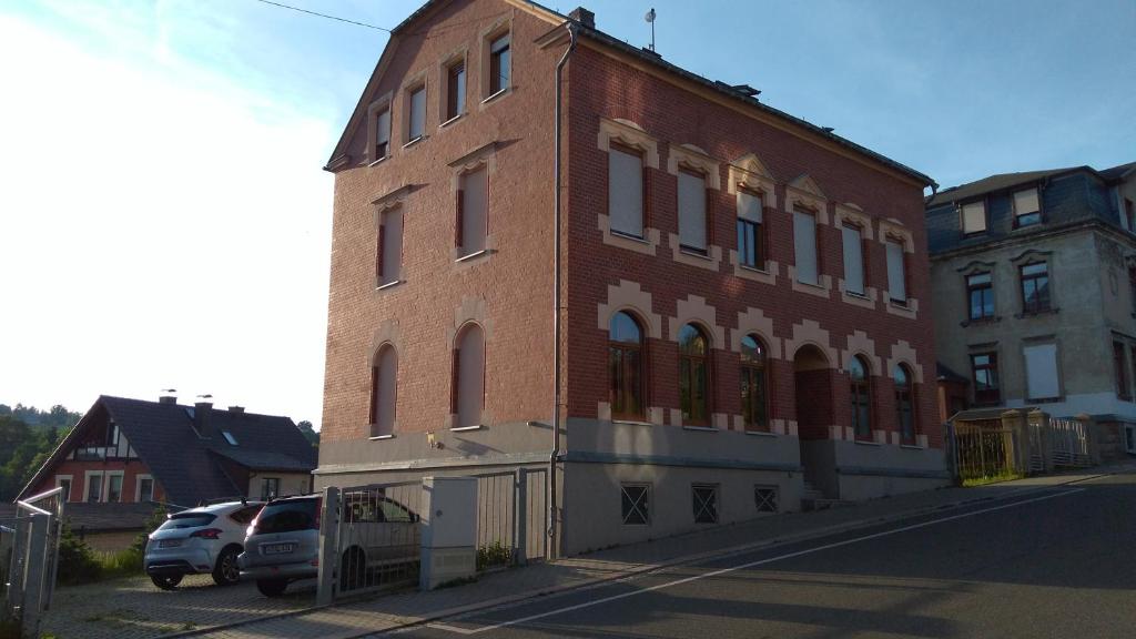 a red brick building with cars parked in front of it at Ferienwohnung KaRo in Ellefeld