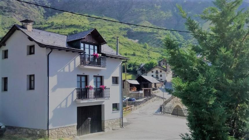 una casa blanca con flores en los balcones de una localidad en Apartaments Pont Romànic, en Espot