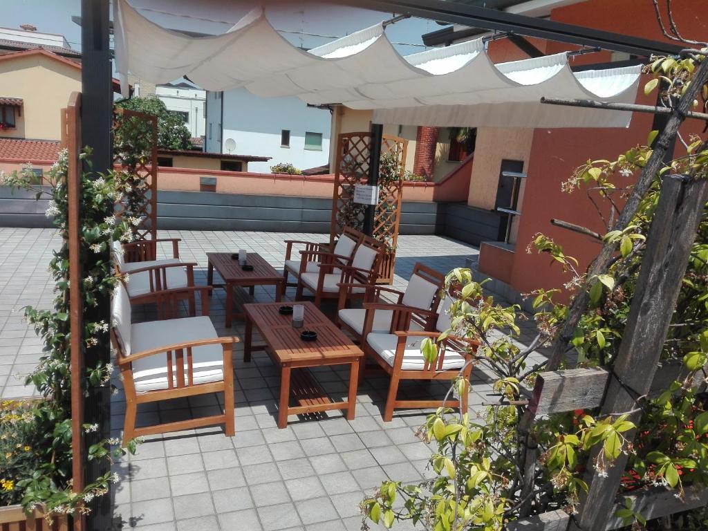 un patio con mesas, sillas y una sombrilla en La Casa Degli Angeli - Agli Angeli Ristorante Pizzeria, en Pertegada