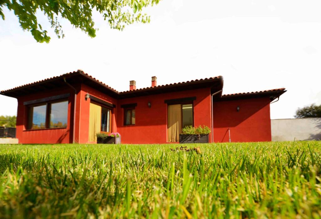 una casa rossa con un prato verde davanti di Casa Rural La Guea de Teruel a Teruel