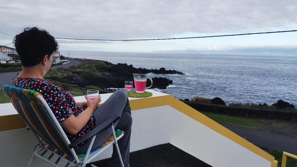 una persona sentada en una mesa con vistas al océano en Casa dos Felicias, en São Roque do Pico