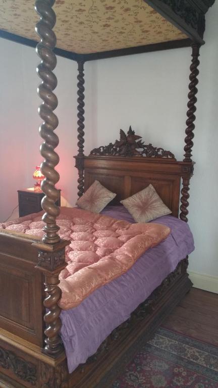ein Himmelbett mit einem Holzrahmen in einem Schlafzimmer in der Unterkunft L'OBSIDIENNE in Lixheim