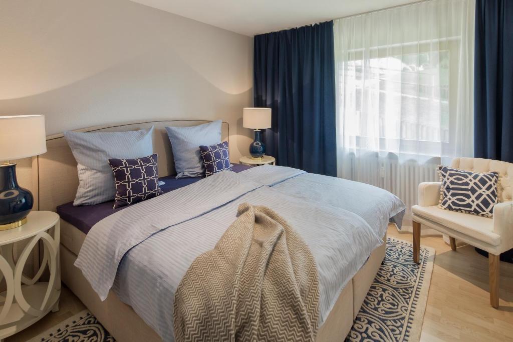 a bedroom with a bed and a chair and a window at Abnoba Mons Design Apartment Lenzkirch in Lenzkirch