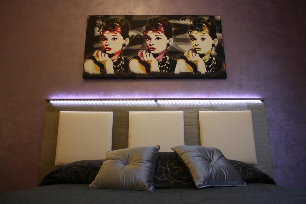 ein Schlafzimmer mit einem Gemälde über einem Bett mit Kissen in der Unterkunft Residenza Elizabeth in Rom