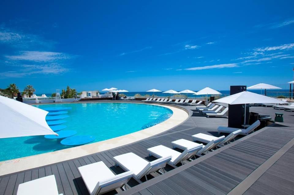 una piscina con tumbonas y sombrillas blancas en Modern 2 Bed Apartment Vale do Lobo en Vale do Lobo