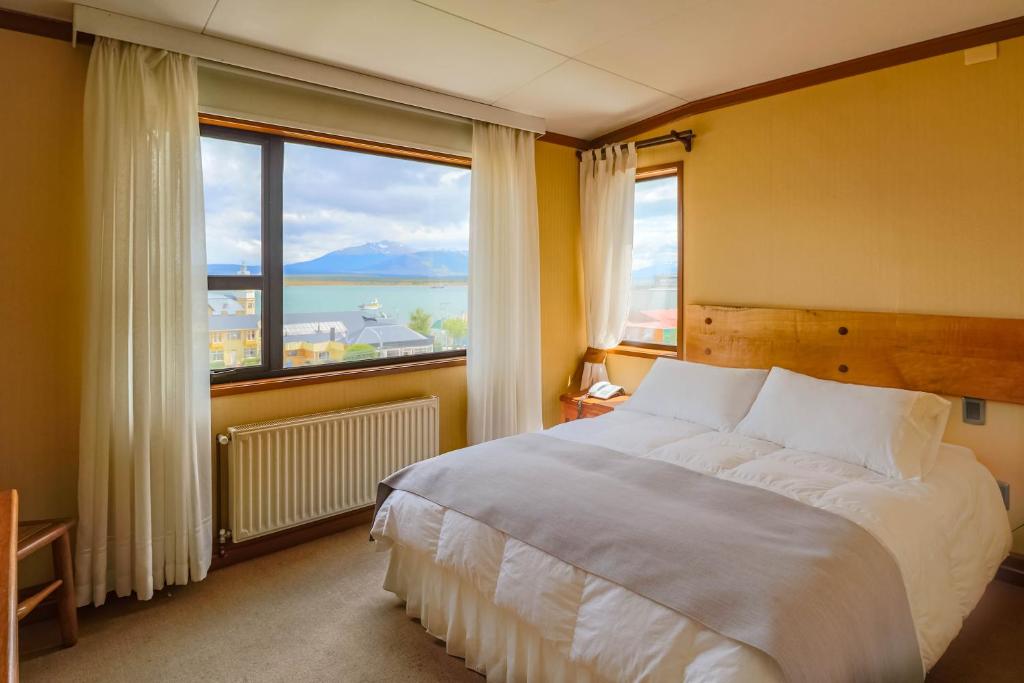 a bedroom with a large bed and a large window at Hotel Saltos del Paine in Puerto Natales