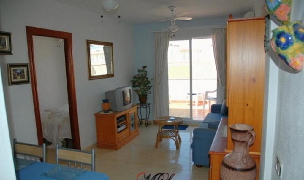 a living room with a blue couch and a tv at One-bedroom flat 200m from the beach in Almería