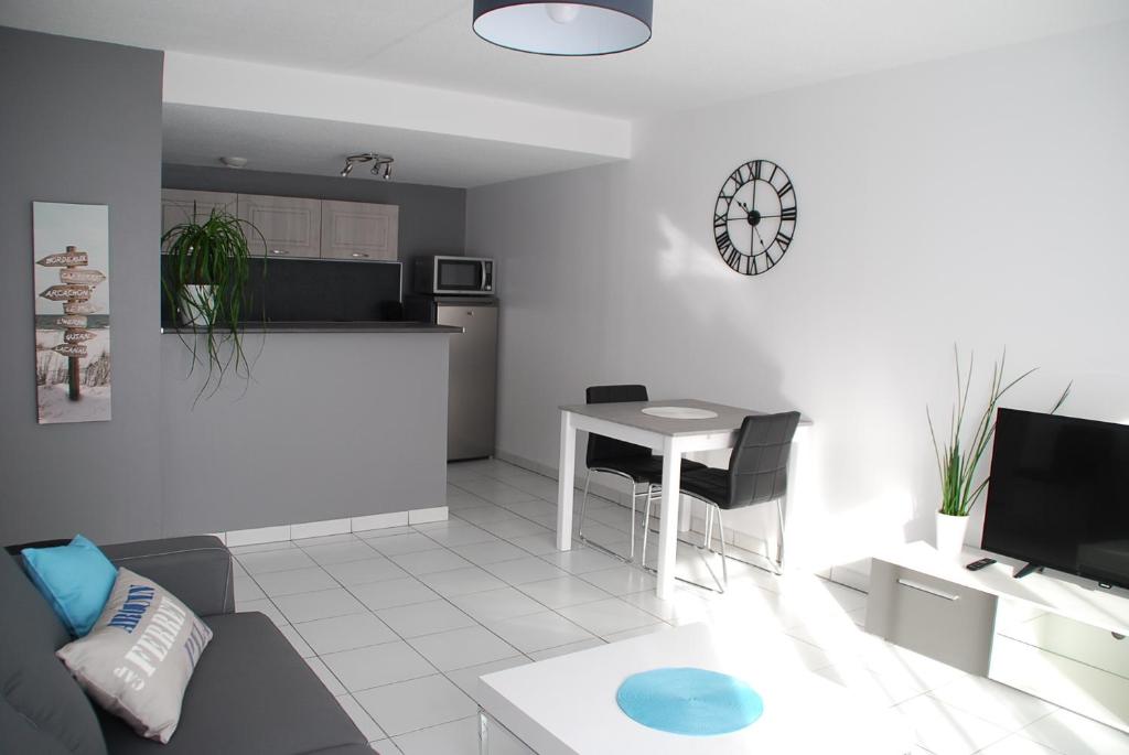 a living room with a couch and a table with a clock at Comme à la maison in Gujan-Mestras