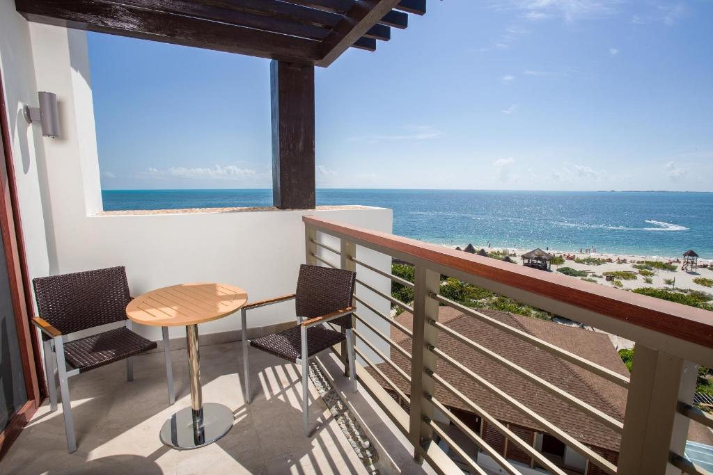 a balcony with a table and chairs and the ocean at Secrets Playa Mujeres Golf & Spa Resort - All Inclusive Adults Only in Cancún