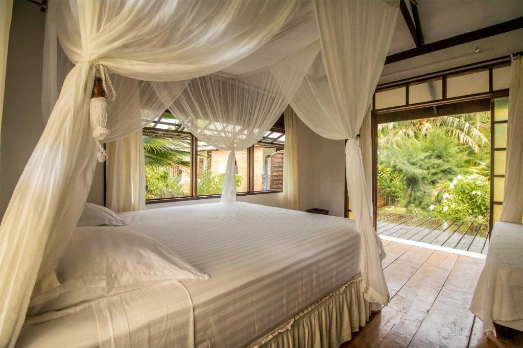 een slaapkamer met een wit bed en een raam bij Le Coconut Lodge in Avatoru