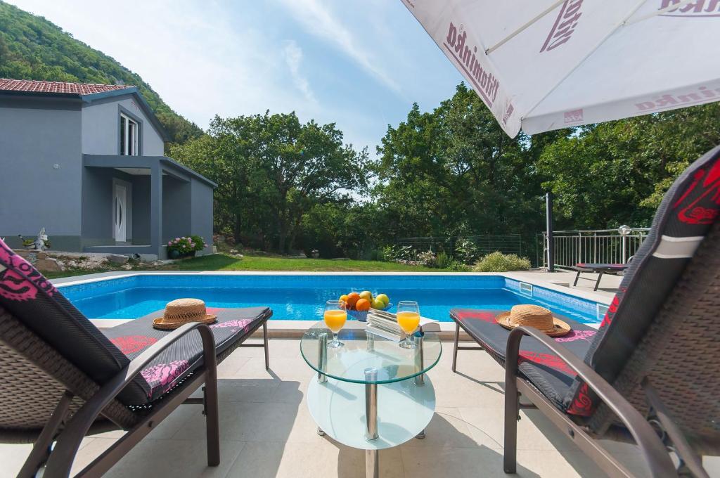 une terrasse avec une table, des chaises et une piscine dans l'établissement Apartments Srdanovic, à Omiš