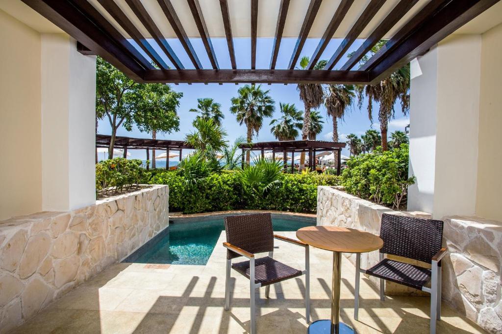 a patio with a table and chairs next to a swimming pool at Secrets Playa Mujeres Golf & Spa Resort - All Inclusive Adults Only in Cancún