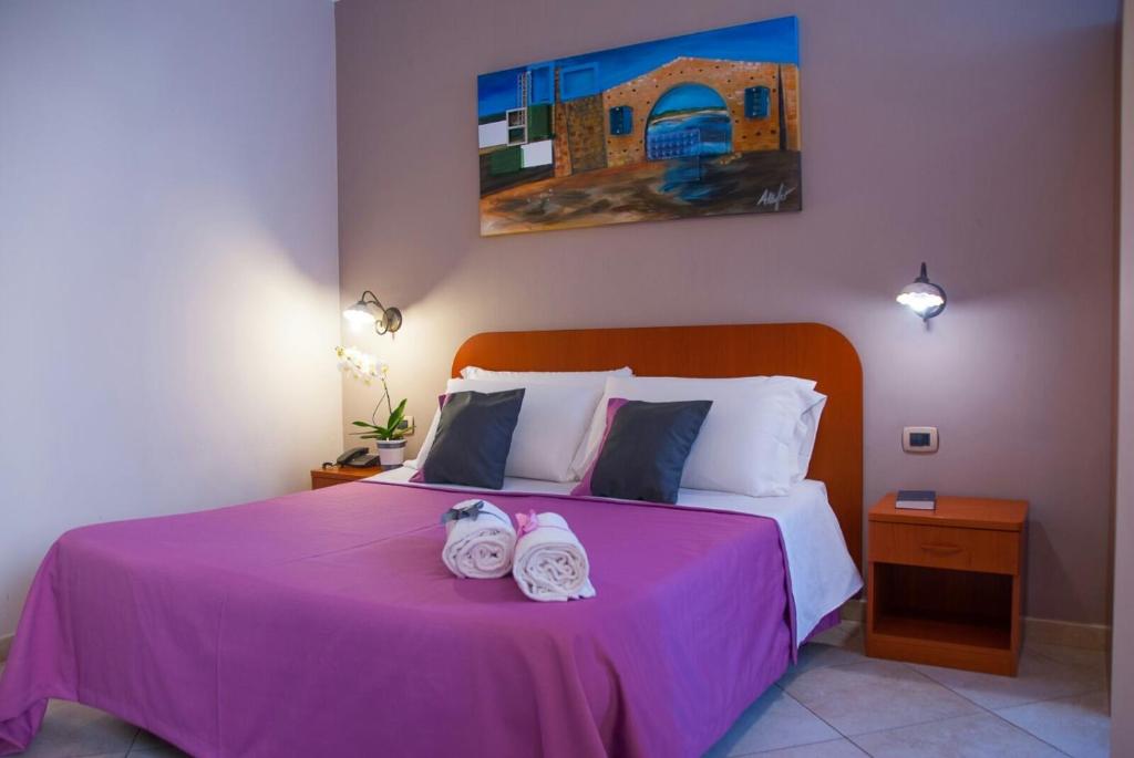 a bedroom with a pink bed with towels on it at B&B Villa Eben Ezer in Avola