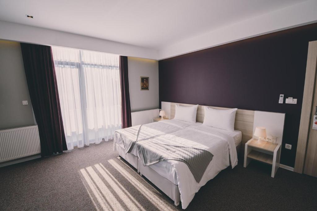 a bedroom with a large bed with a black wall at Hotel Nova Bentbaša in Sarajevo