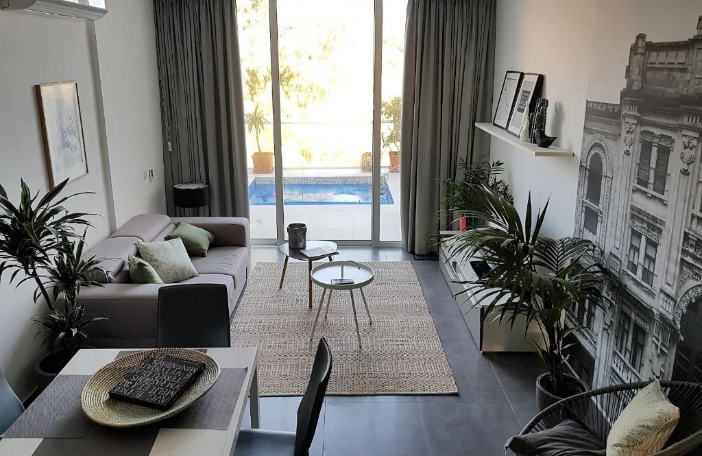 een woonkamer met een bank en een aantal planten bij Duplex Maisonette with Heated P-Pool and Jacuzzi in St Julian's