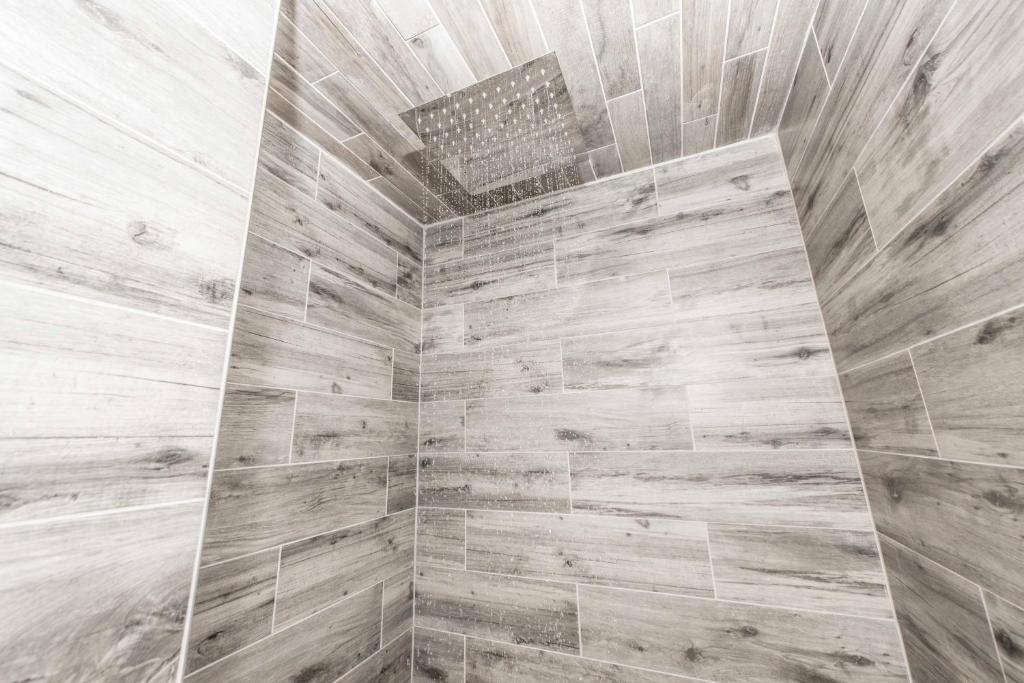 a bathroom with a large shower with wooden tiles at Ember Hostel in Denver