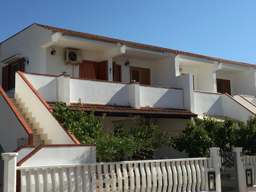 uma casa branca com escadas e uma cerca em Yucca Apartment em San Vito lo Capo