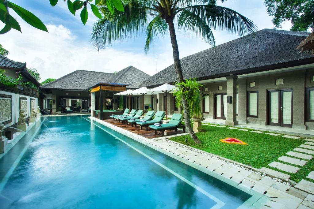 a villa with a swimming pool and lounge chairs at Villa Dewata II in Seminyak
