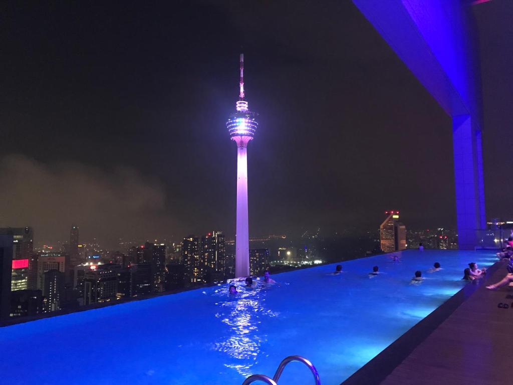 a swimming pool at night with the sky needle at 7Stonez Platinum Residence KLCC in Kuala Lumpur